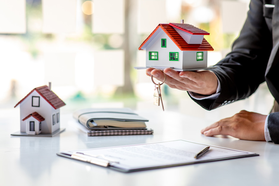 Businessman in suit showcasing house model.