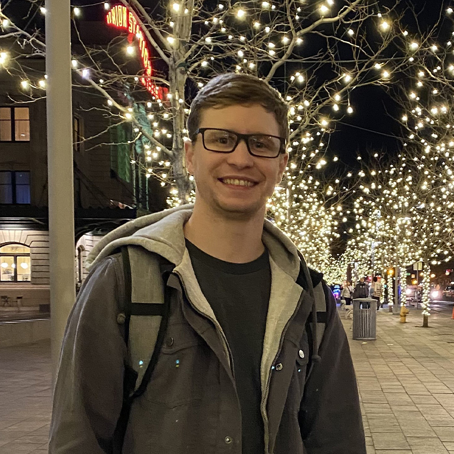 Tyson Johnson, a bespectacled man, posing proudly in front of a beautifully adorned Christmas tree.